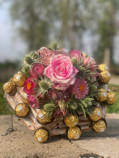 Blumenstrauß mit Manschette aus Roché Kugeln Amicelli Riegeln und passend farbigen Blumen.