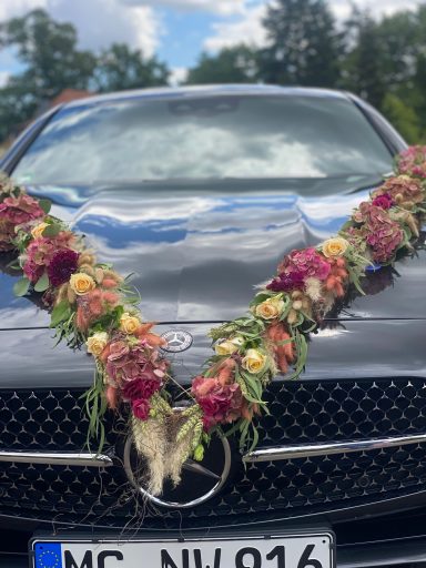 Mehrfarbige Blumengirlande zur Dekoration auf schwarzer Hochzeits Limousine.
