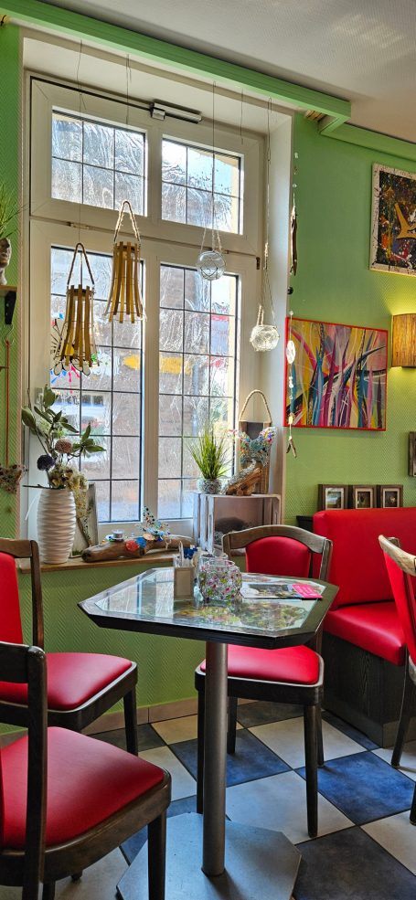 Bestuhlte und dekorierte Sitzecke am Fenster im Blumen Kunst Café Alles-Petra