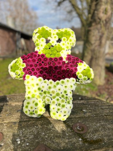 Blumengesteck in Form eines Teddybären für eine Beerdung eines Kindes.