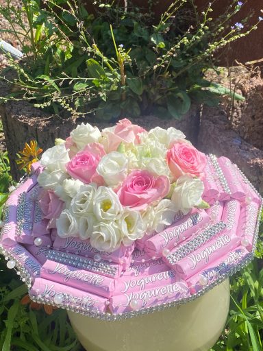 Blumenstrauß mit Manschette aus Joghurette Riegeln und passend farbigen Rosen in rosa und weiß.